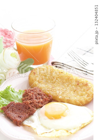 目玉焼きとハッシュドポテトとコンビーフの朝食プレートとキャロットジュース 132404851