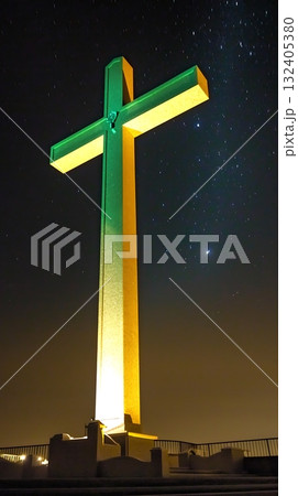 Large green and yellow cross is lit up at night 132405380