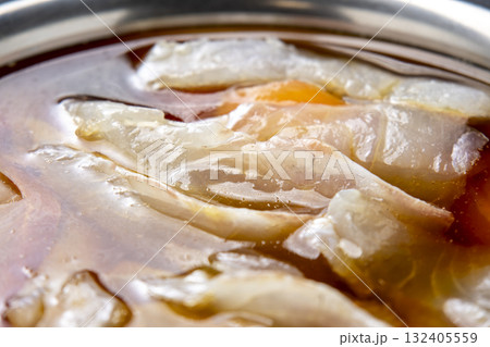 生魚の切り身を漬けダレに漬ける調理シーン。 132405559