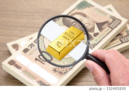 札束の上に置かれたゴールドのインゴットをクローズアップ 132405830