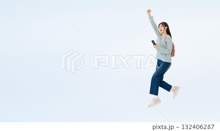 スマホを持ってジャンプする女子学生の全身写真 スマホを持ってジャンプする女子学生の全身写真 132406287
