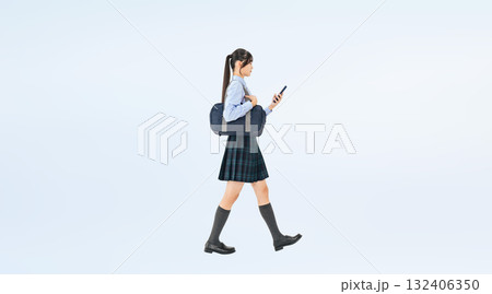スマホを見ながら歩く制服の女子学生の全身写真 132406350