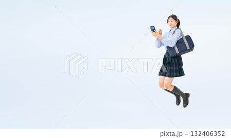 スマホを持ってジャンプする制服の女子学生の全身写真 スマホを持ってジャンプする制服の女子学生の全身写真 132406352