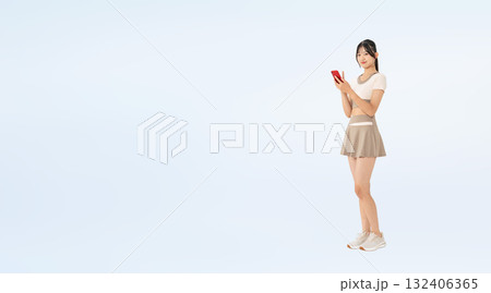 スマホを使うスポーツウェアの女性の全身写真 132406365