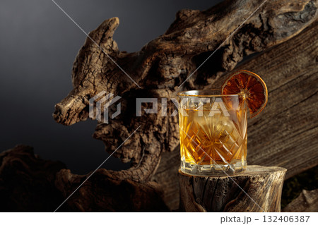 Old-fashioned cocktail with ice and dried orange slice. 132406387