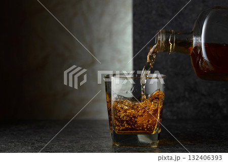 Pouring whiskey from a bottle into a glass. Pouring whiskey from a bottle into a glass. 132406393