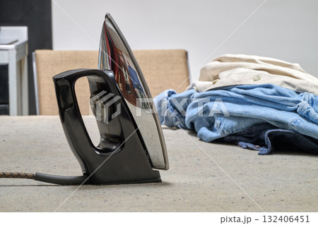 an iron and shirts on table 132406451