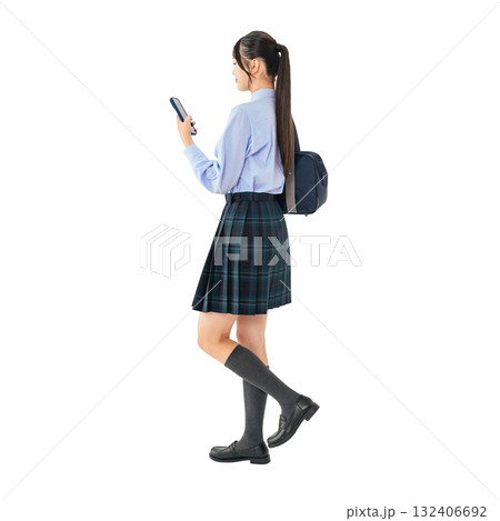 スマホを見ながら歩く制服の女子学生　手作業で精密に切り抜いた背景透過全身写真PNG 132406692