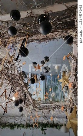 A whimsical ceiling decoration with natural branches, black and white balloons, and sparkling golden stars hanging over a doorway.. A whimsical ceiling decoration with natural branches, black and white balloons, and sparkling golden stars hanging over a doorway.. 132407643