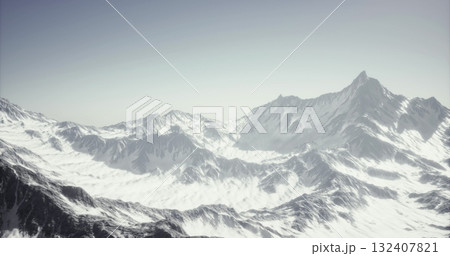 Majestic peaks rise dramatically against a clear sky, blanketed in shimmering snow. The tranquil landscape reveals the stunning beauty of untouched wilderness in the early morning light. 132407821