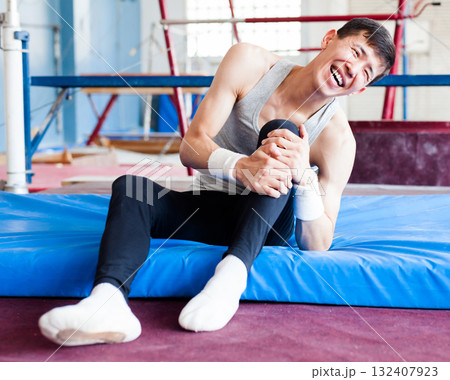 Gymnast clutching knee in pain during training in gym 132407923