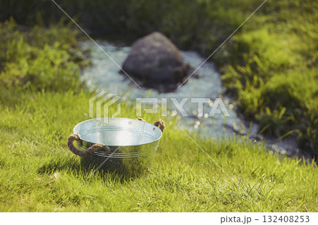 Old wash basin in the yard by the stream 132408253