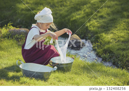 Charming girl washing clothes in the garden. Retro portrait 132408256