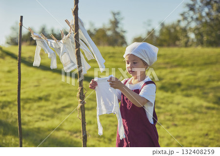 Charming girl washing clothes in the garden. Retro portrait 132408259