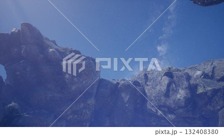 Majestic cliffs rise against a backdrop of bright blue skies, with wispy clouds drifting above. The rocky terrain showcases the beauty of untouched wilderness, inviting exploration. 132408380