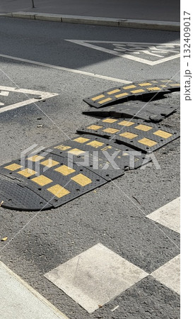 Damaged speed bump on asphalt road with yellow markings for traffic safety background Damaged speed bump on asphalt road with yellow markings for traffic safety background 132409017
