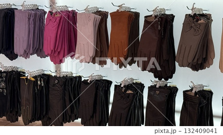 Gloves displayed in various colors and styles on hangers in store setting 132409041