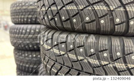 Close-up of stacked winter tires with metal studs, suitable for background in automotive themes 132409046
