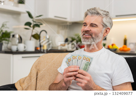 Middle-aged man counts money cash dollars smiles at plans purchase salary bonus savings investment Middle-aged man counts money cash dollars smiles at plans purchase salary bonus savings investment 132409077
