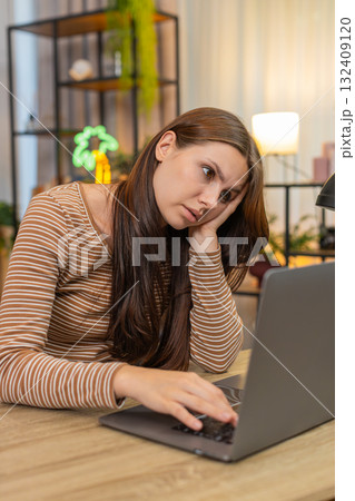 Young woman sits at laptop leans on hand looks so sad unmotivated to continue work emotional burnout 132409120