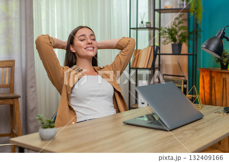 Young woman closing laptop leaning back with relief after finishing work smiling enjoying victory Young woman closing laptop leaning back with relief after finishing work smiling enjoying victory 132409166