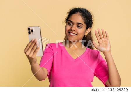 Indian woman energetically waving, filming herself talking and smiling, recording engaging video Indian woman energetically waving, filming herself talking and smiling, recording engaging video 132409239