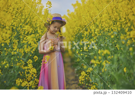 charming child in sundress in a rapeseed field charming child in sundress in a rapeseed field 132409410