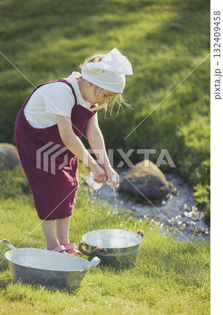 Charming girl washing clothes in the garden. Retro portrait 132409458