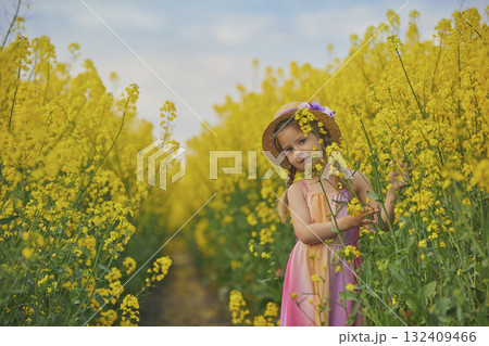 charming child in sundress in a rapeseed field charming child in sundress in a rapeseed field 132409466