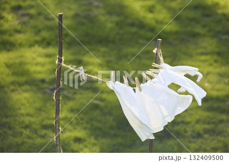Washed clothes drying on a clothesline in the yard Washed clothes drying on a clothesline in the yard 132409500