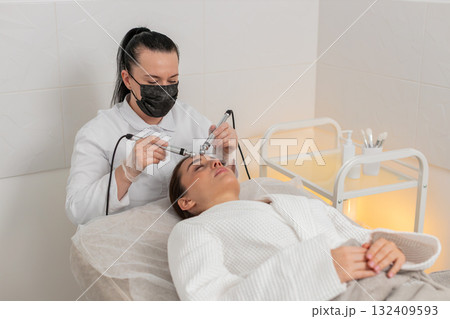 Beautician doctor makes woman micro currents face therapy using electrical impulses in spa salon Beautician doctor makes woman micro currents face therapy using electrical impulses in spa salon 132409593