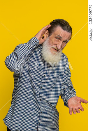 Senior old man trying hear you looking confused and frowning keeping arm near ear for louder voice Senior old man trying hear you looking confused and frowning keeping arm near ear for louder voice 132409779