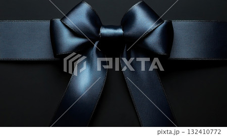Elegant black satin ribbon in a bow shape on a black background, symbolizing mourning or grief. 132410772