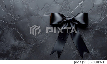Elegant black satin ribbon in a bow shape on a black background, symbolizing mourning or grief. Elegant black satin ribbon in a bow shape on a black background, symbolizing mourning or grief. 132410921