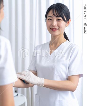 白衣と手袋姿で患者に微笑む看護師の穏やかな瞬間 132411082