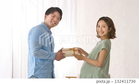 妊婦さんにプレゼントを渡す若いパートナー 132411730