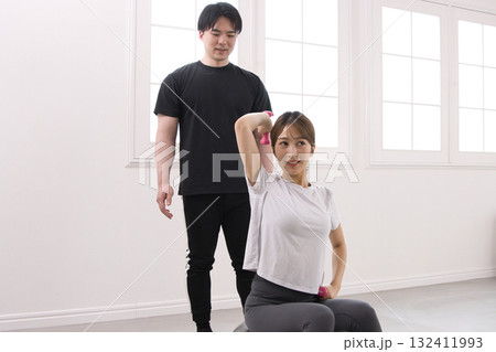 パーソナルトレーナーにトレーニングを受ける若い女性 132411993