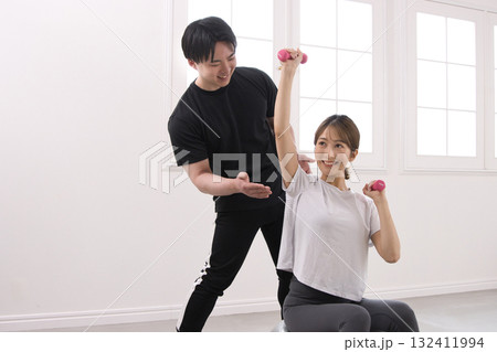 パーソナルトレーナーにトレーニングを受ける若い女性 132411994