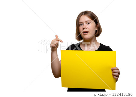 Young woman gesturing and speaking while holding a yellow poster, isolated on white background. 132413180