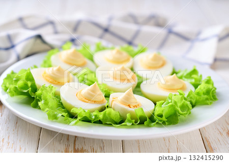 light snack of hard boiled chicken eggs and mayonnaise on a white table. light snack of hard boiled chicken eggs and mayonnaise on a white table. 132415290