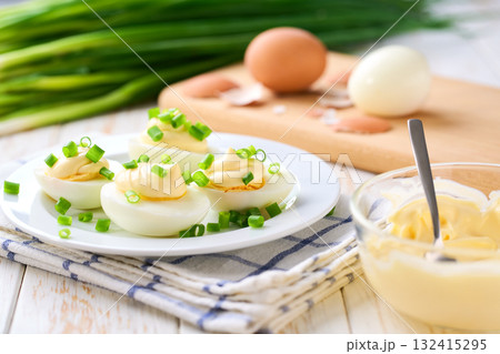 Healthy breakfast concept, boiled chicken eggs with mayonnaise and freshly cut chives on a wooden table. Healthy breakfast concept, boiled chicken eggs with mayonnaise and freshly cut chives on a wooden table. 132415295