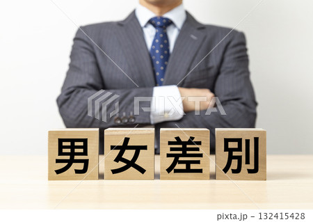 「男女差別」と書かれたブロックと腕組みをするビジネスマン 132415428
