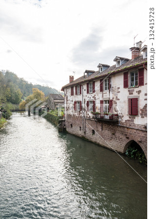 朝もやの中の川沿いに立つ歴史的な建物と木々 フレンチバスク地方のサン・ジャン・ピエ・ド・ポールにて 朝もやの中の川沿いに立つ歴史的な建物と木々 フレンチバスク地方のサン・ジャン・ピエ・ド・ポールにて 132415728