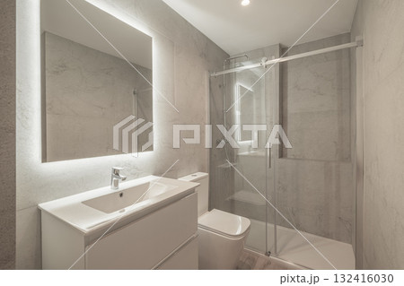 Modern bathroom with a glass shower, white sink, and large mirror. Neutral gray tiles create a sleek and clean aesthetic. Modern bathroom with a glass shower, white sink, and large mirror. Neutral gray tiles create a sleek and clean aesthetic. 132416030