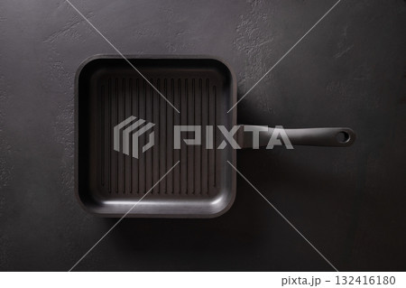 Empty cast iron grill pan with handle on black background. View from above. Empty cast iron grill pan with handle on black background. View from above. 132416180