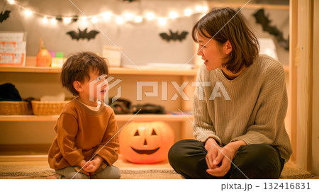 秋の夜のリビングで母と子がジャックオーランタンの前で談笑 132416831