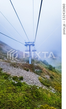 A ski lift ride in the mountains in the fog 132416960