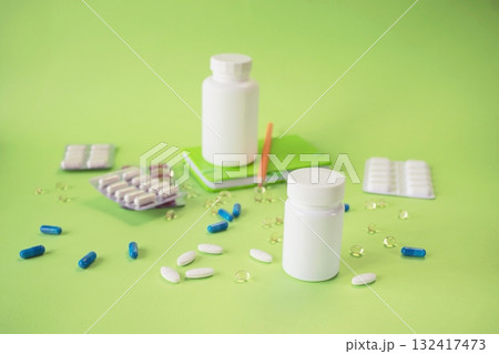 An assortment of pills and medicine bottles. Various tablets and capsules on a green background, symbolizing medicine, pharmacy, drug delivery, and sales. An assortment of pills and medicine bottles. Various tablets and capsules on a green background, symbolizing medicine, pharmacy, drug delivery, and sales. 132417473