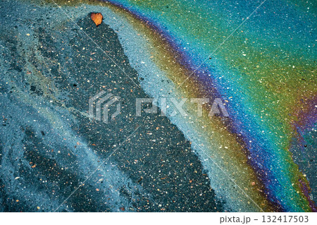 Oil spill forming a colorful iridescent pattern on wet street asphalt, showing pollution. 132417503