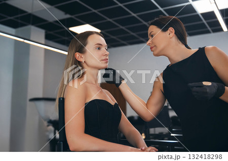 Makeup artist applies foundation to model in trendy salon during daytime beauty session Makeup artist applies foundation to model in trendy salon during daytime beauty session 132418298